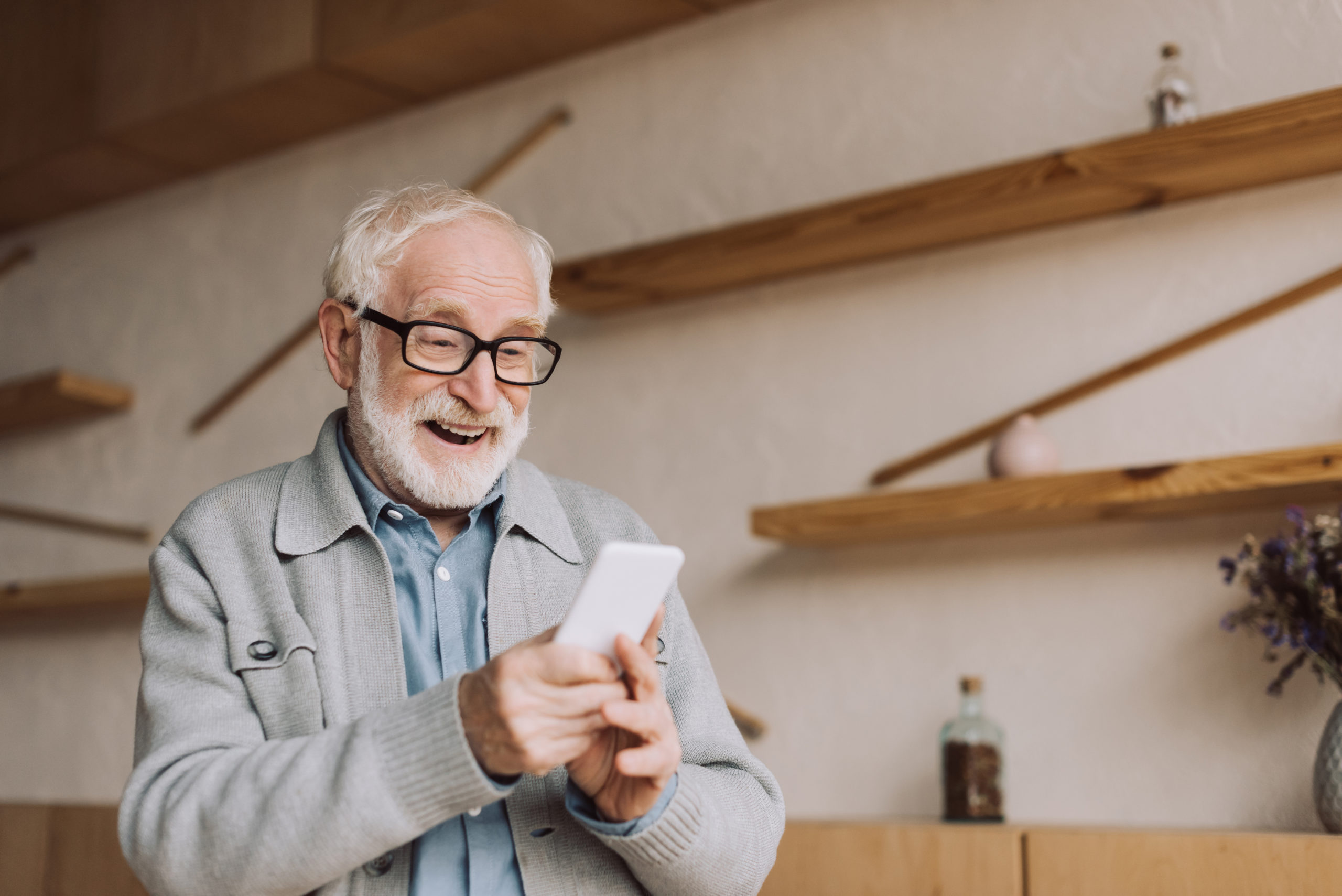 happy senior man using smartphone and looking at camera